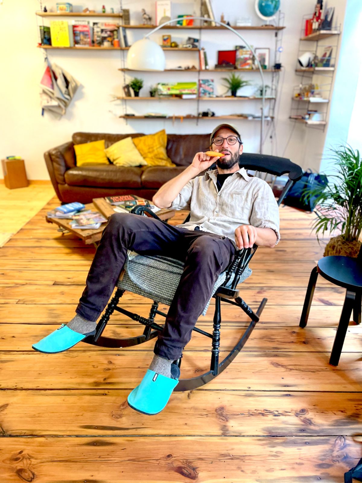 Bertram sitzt in einem Schaukelstuhl im STUDIO 21. Er hält sich eine Karotte wie eine Zigarre an den Mund und lacht in die Kamera.